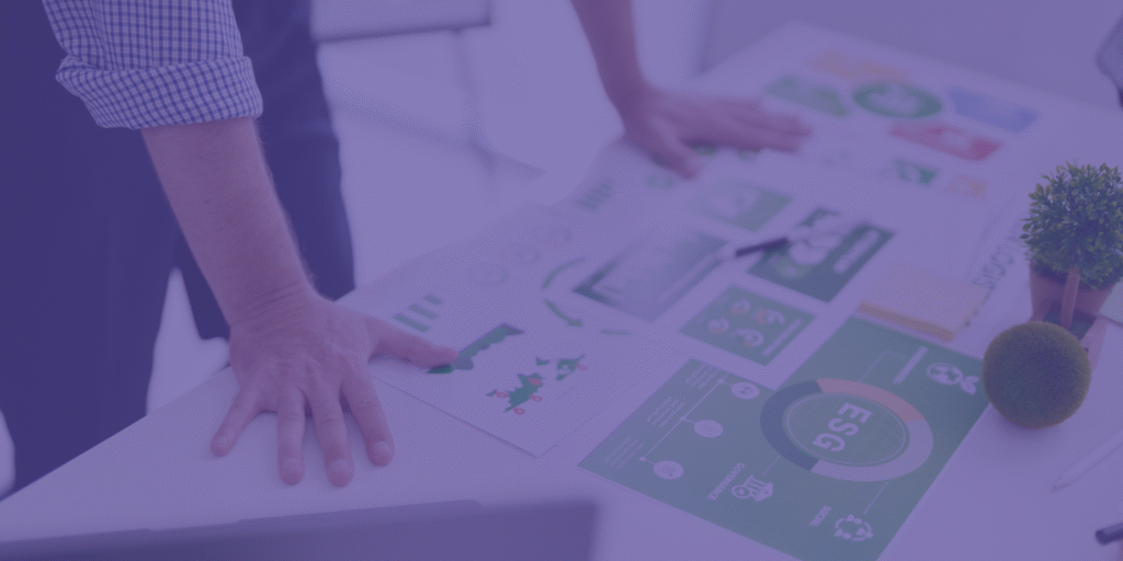 Pessoa a analisar relatórios e gráficos sobre ESG numa mesa de trabalho, representando a importância da sustentabilidade e governança no contexto empresarial.