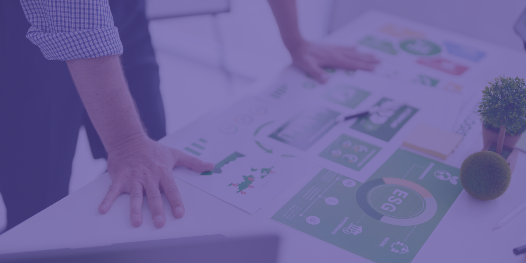 Pessoa a analisar relatórios e gráficos sobre ESG numa mesa de trabalho, representando a importância da sustentabilidade e governança no contexto empresarial.